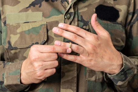 Man in military uniform taking off wedding ring