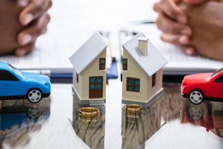 Toy house split into two with wedding rings on the table