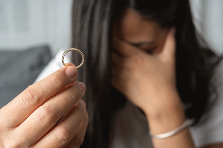 Women holding wedding ring looking stressed